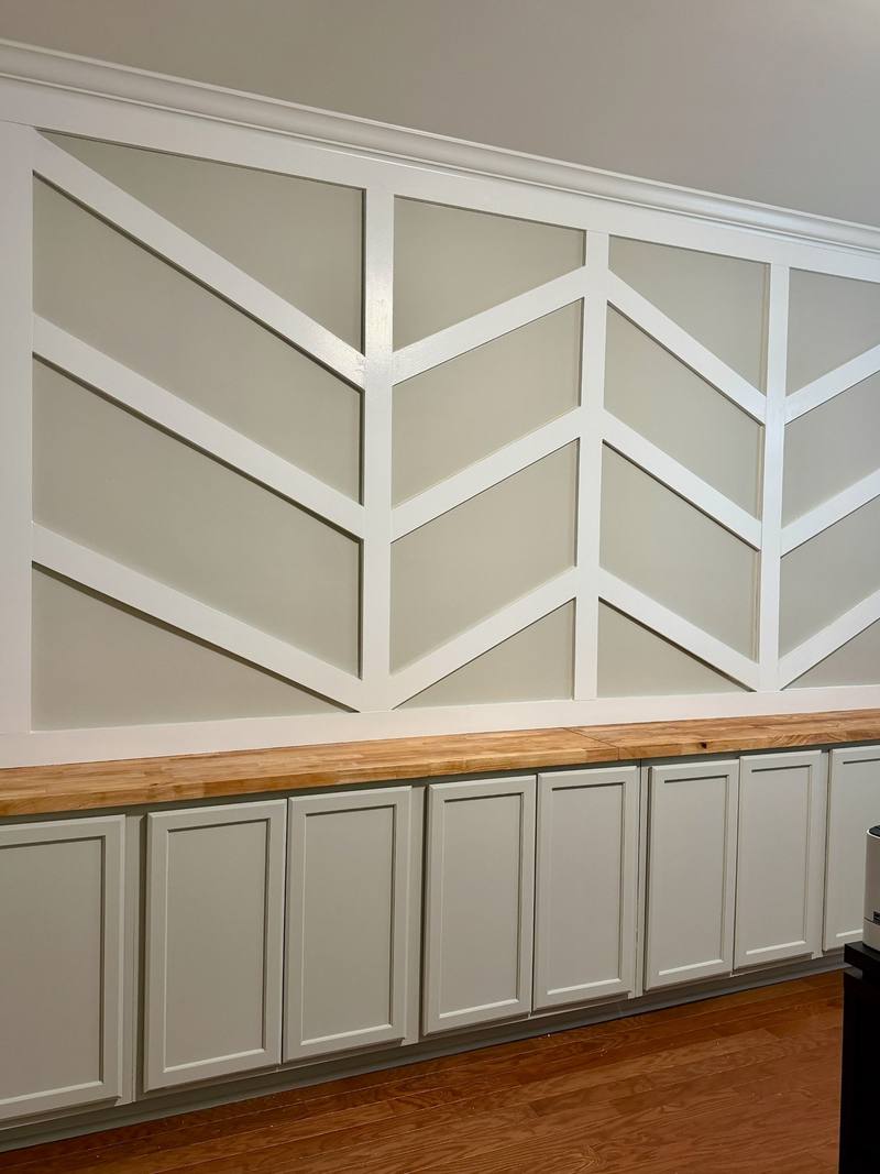 Chevron trim accent wall above built-in cabinets