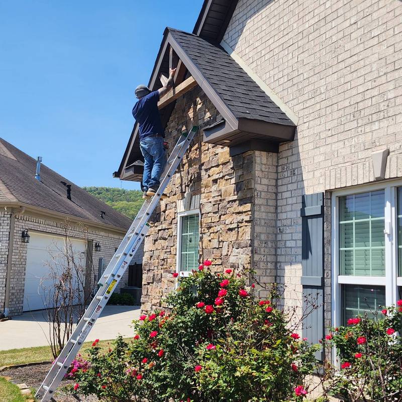 Crew installing decorative trim on a stone and brick gable