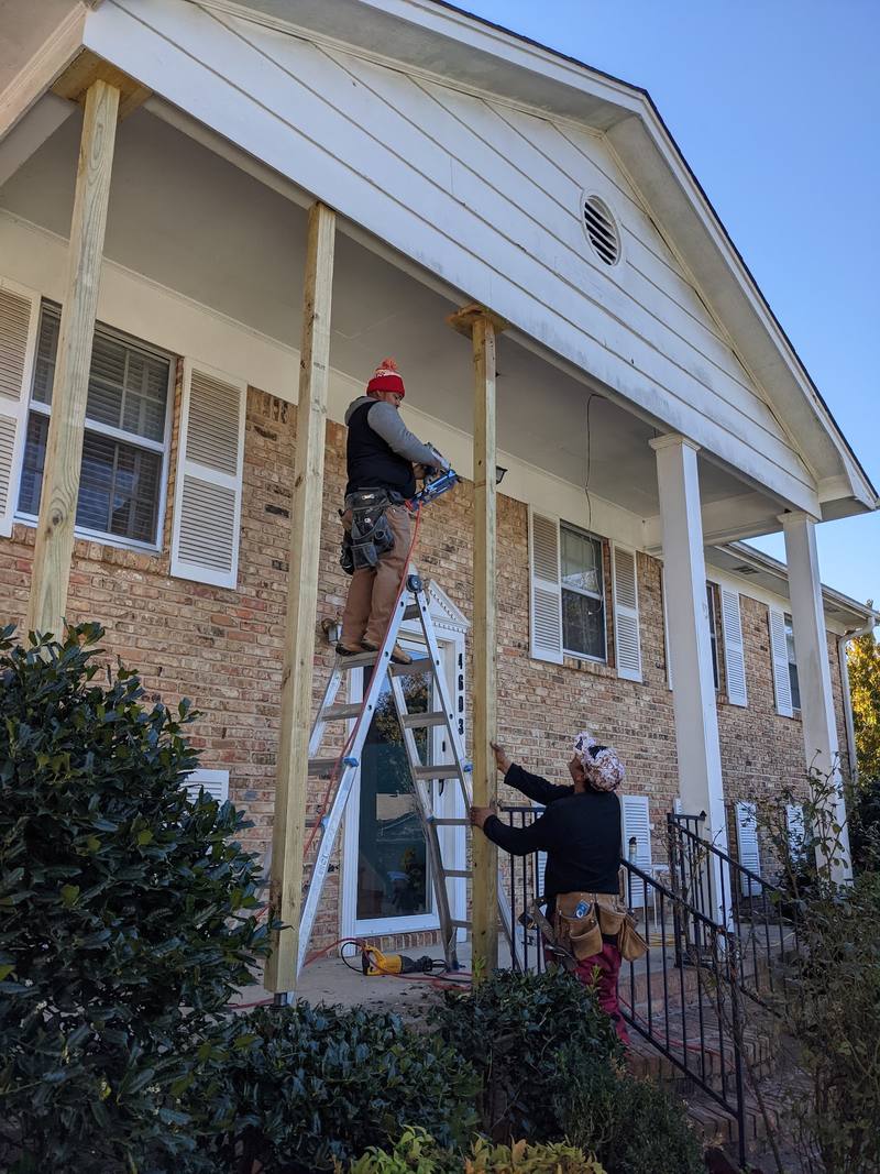 Crew repairing exterior trim on a front porch