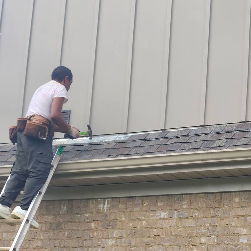 Crew repairing flashing where the roof meets the siding